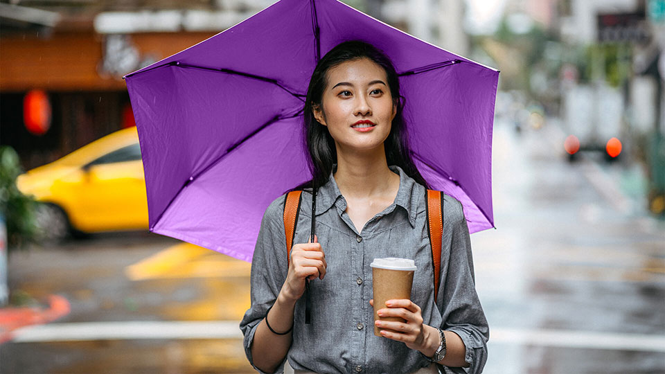 Femme tenant un café et un parapluie violet