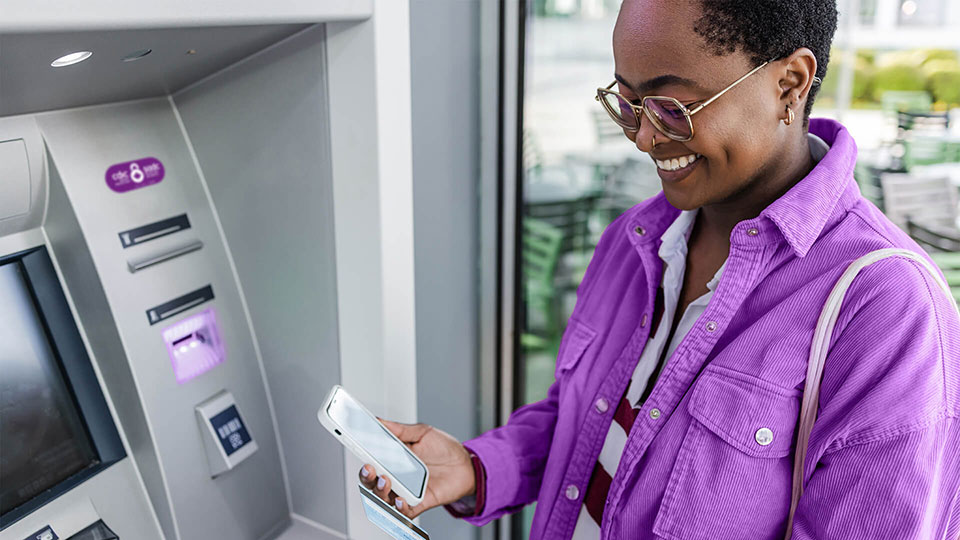 Femme à un distributeur automatique de billets avec un autocollant de la SADC